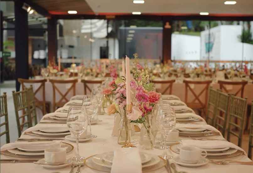 Mesa posta com velas, arranjos de flores rosas e cadeiras tiffany